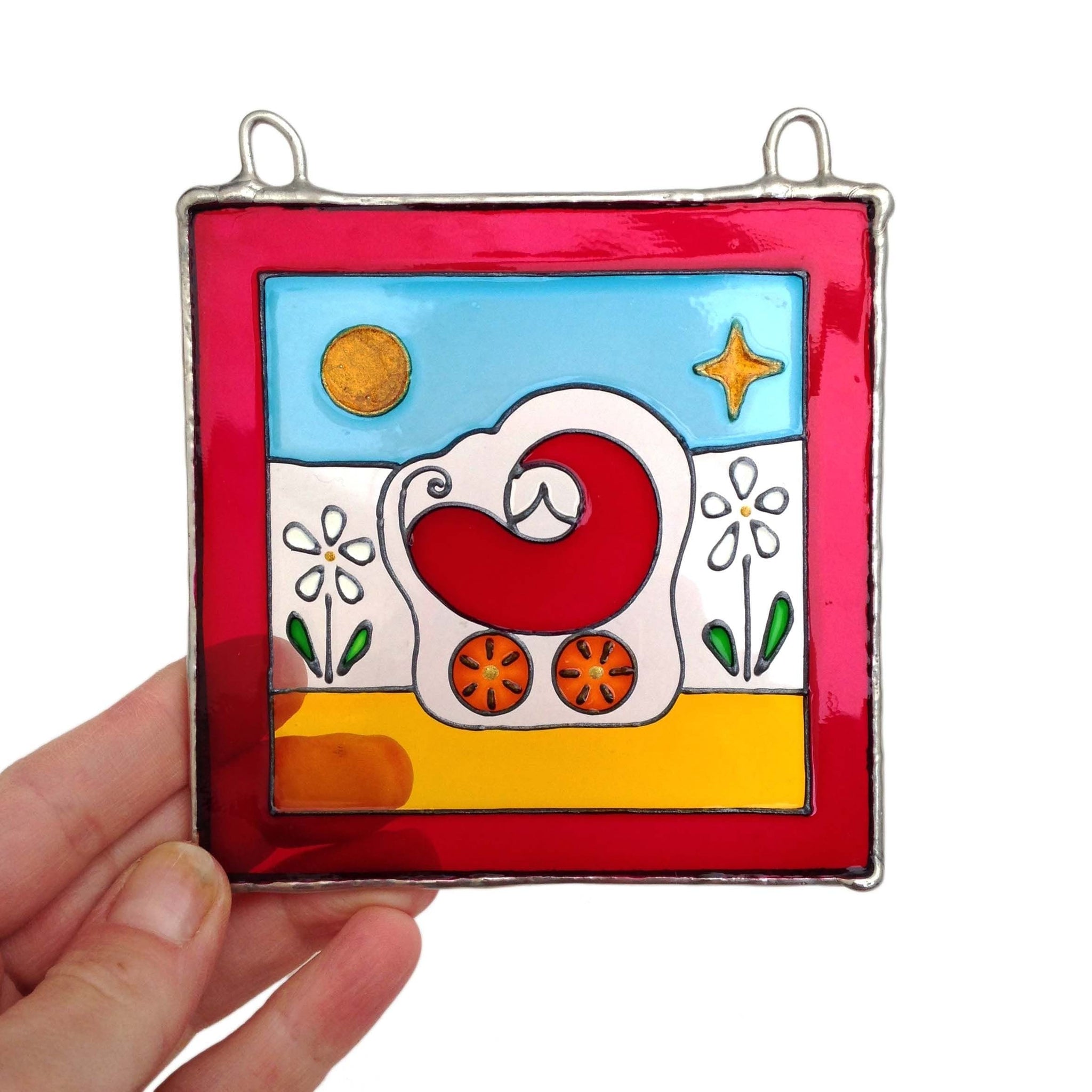 LeKoky girl's version of the hand-painted glass suncatcher featuring a baby in a pram design, being held by a person to show its size - perfect as a Christening or New Born welcoming gift