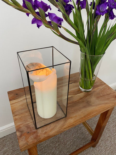 "A handmade glass candle holder from Lekoky, showcasing a lit candle and flower bouquet in a home setting. Crafted by a skilled stained glass artist in Southampton, Hampshire, England.