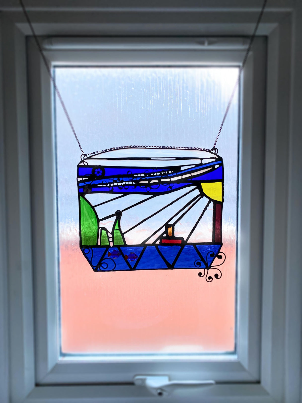 Stained glass suncatcher with chain for easy hanging, reflecting light beautifully.